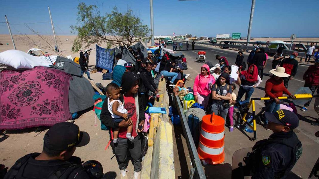 Policías peruanos (abajo) vigilan a cientos de migrantes varados en la frontera, en Arica (Chile). EFE Perú